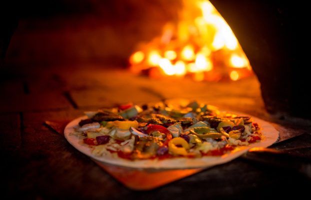 Delicious vegetarian pizza going into a wood fire oven Delicious vegetarian pizza going into a wood fire oven